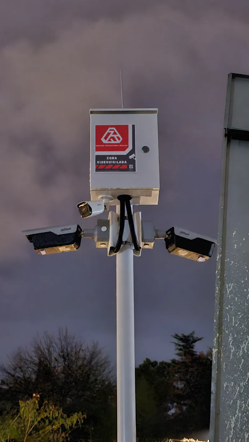 Pole-mounted surveillance cameras with a Quesada Instalaciones Técnicas sign